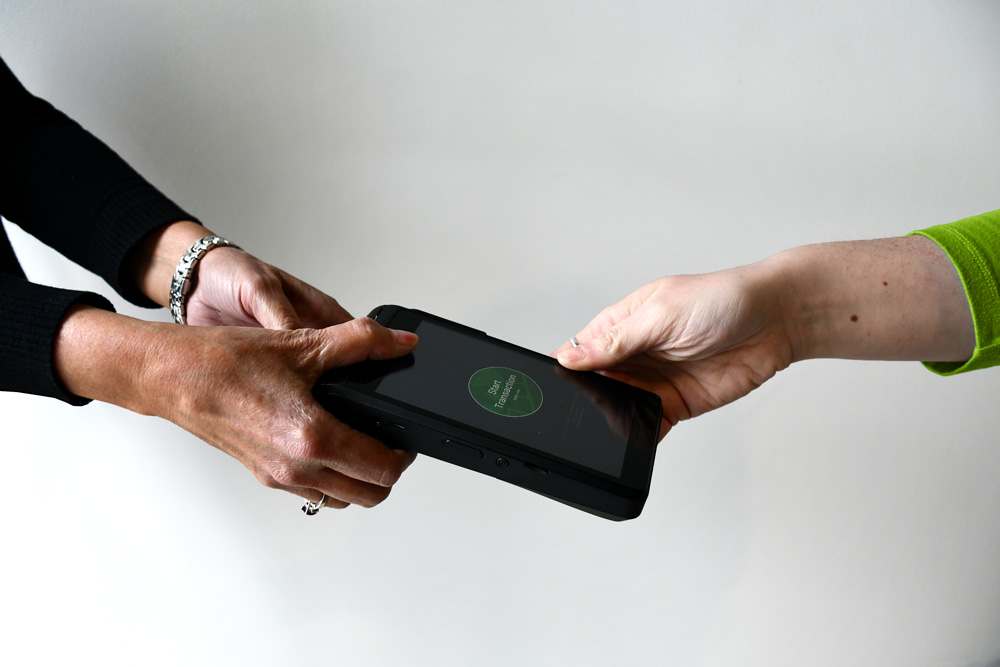 A woman handing over the cannabis payment processor equipment over to another woman